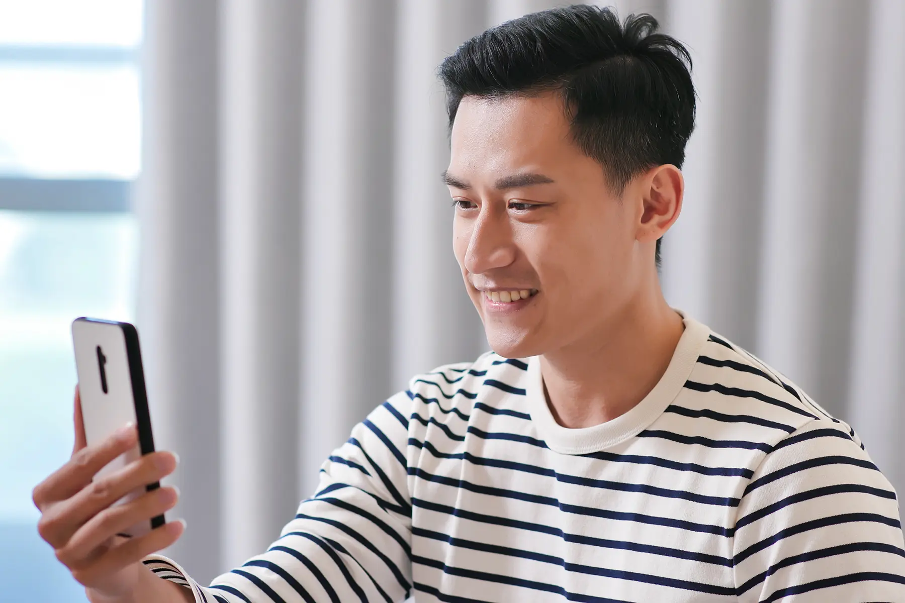 Man smiling while on a virtual call with a doctor from his phone