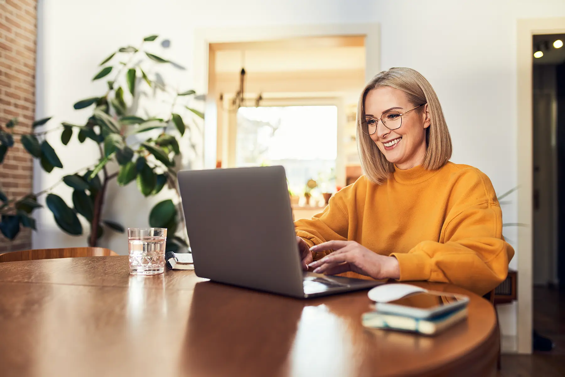 Woman sitting at her table and smiling at her computer.