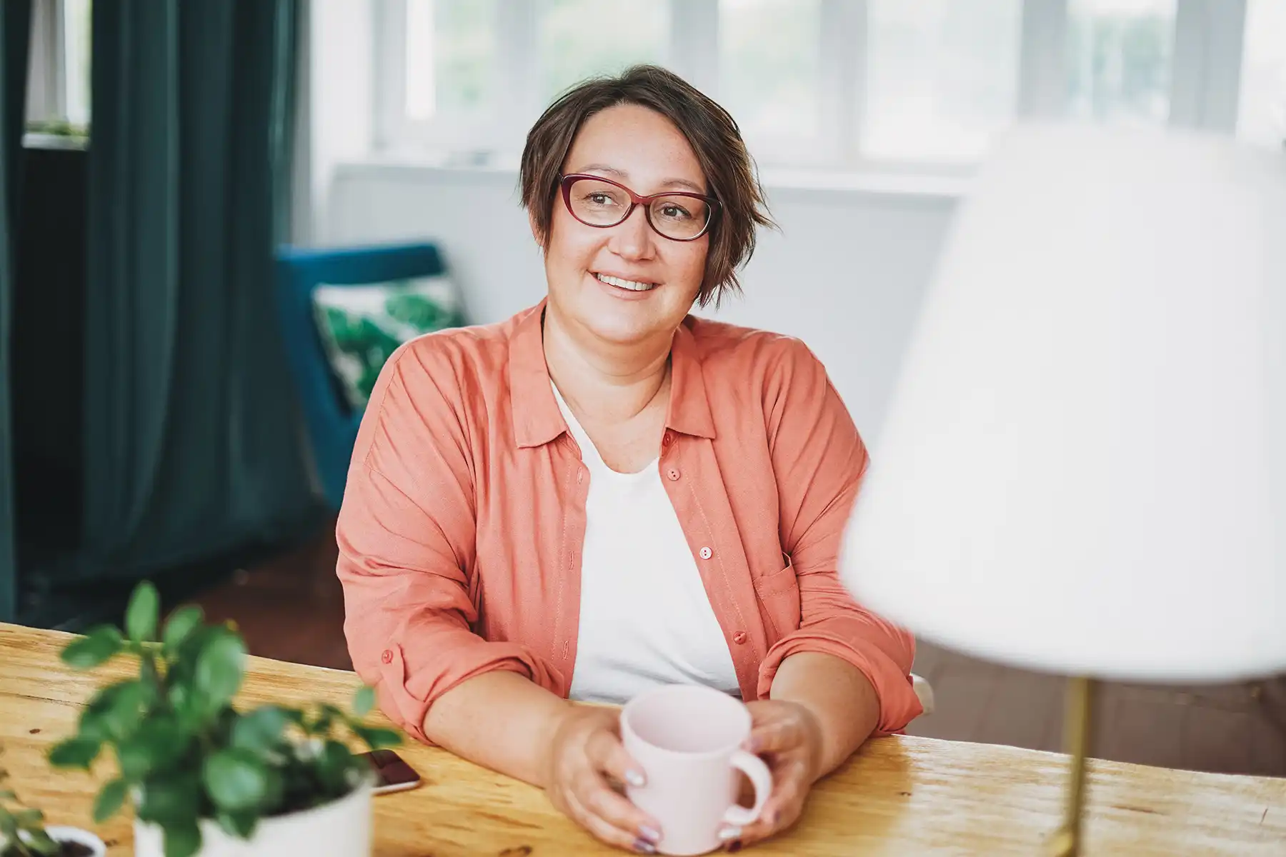 Menopausal woman who could benefit from GLP-1s sitting at her kitchen table. 