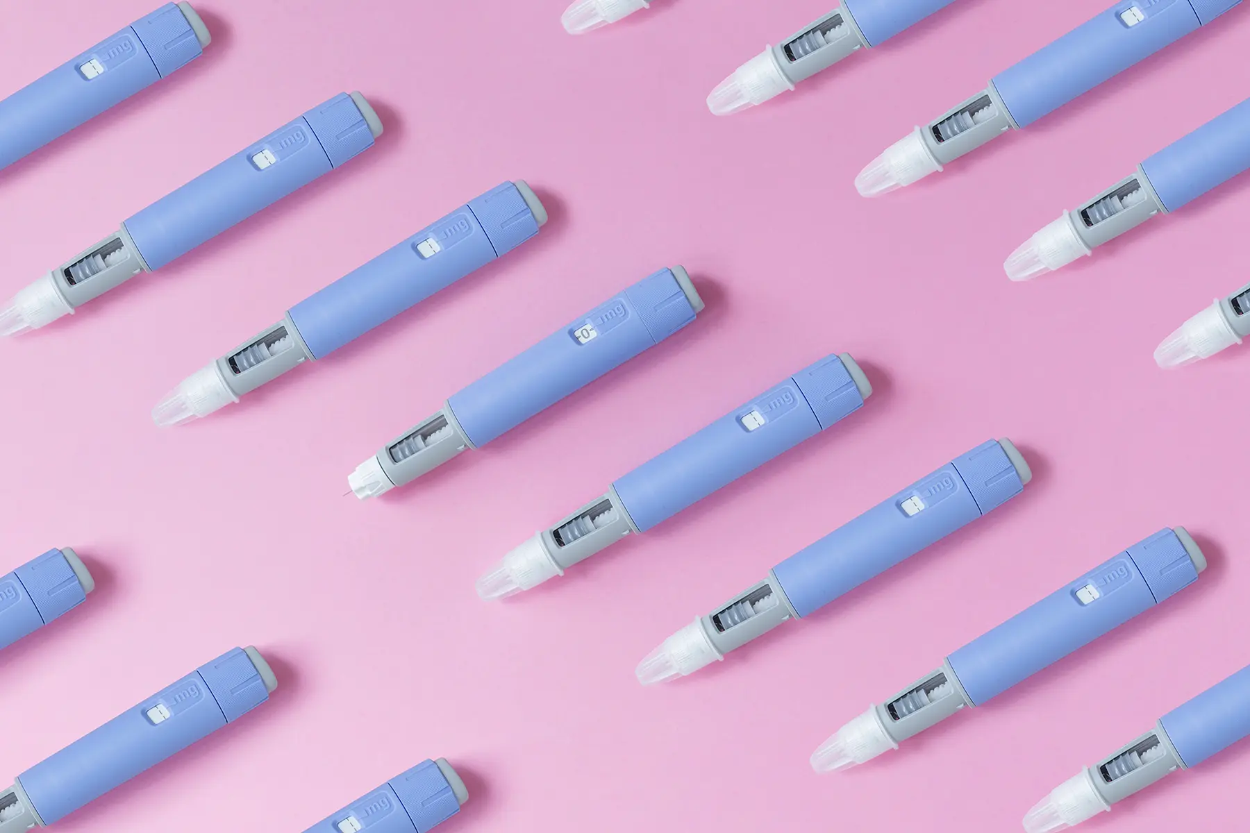 Lines of GLP-1 pens in front of pink background.