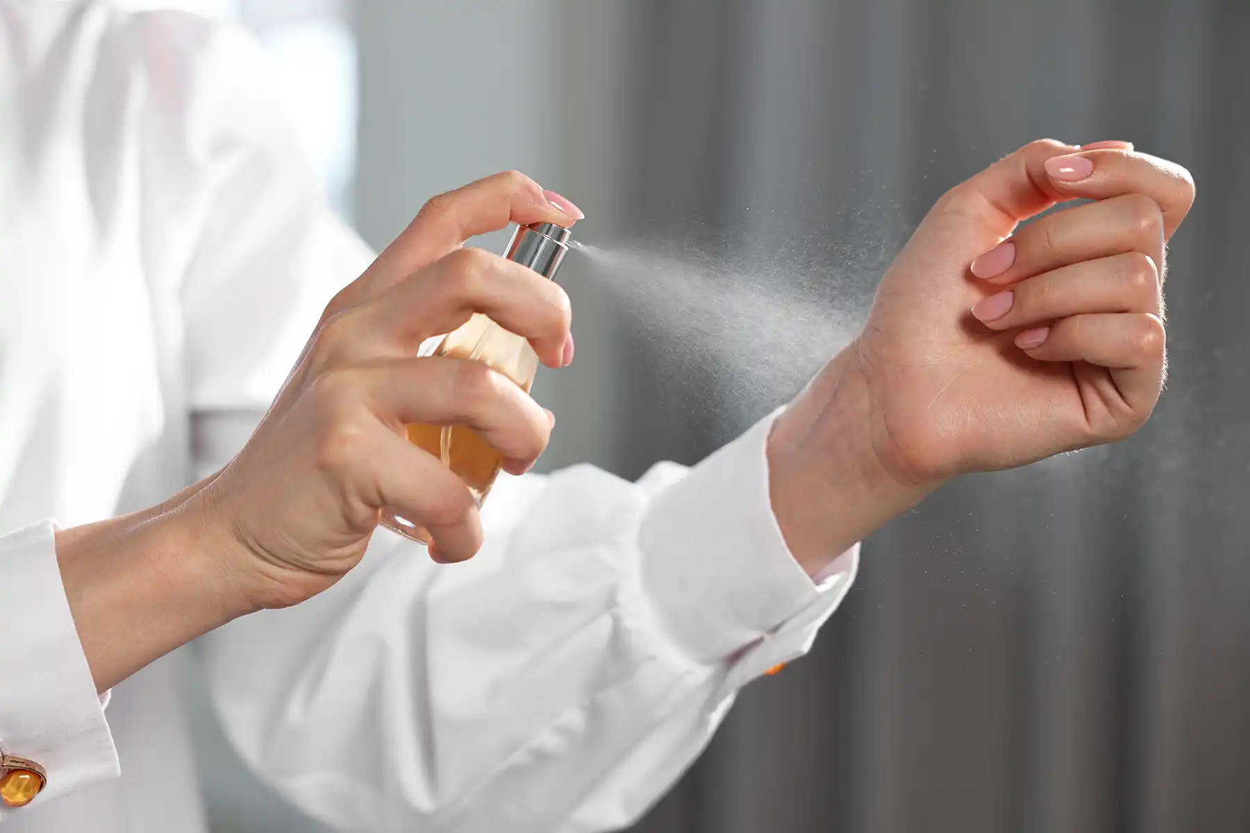 Woman spritzing perfume on her wrist.