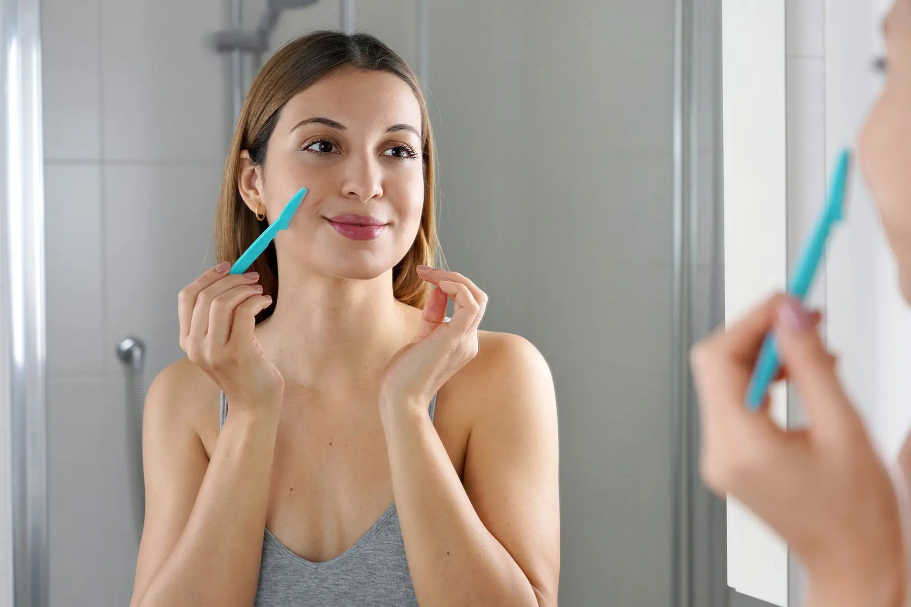 Picture of a female shaving her face.