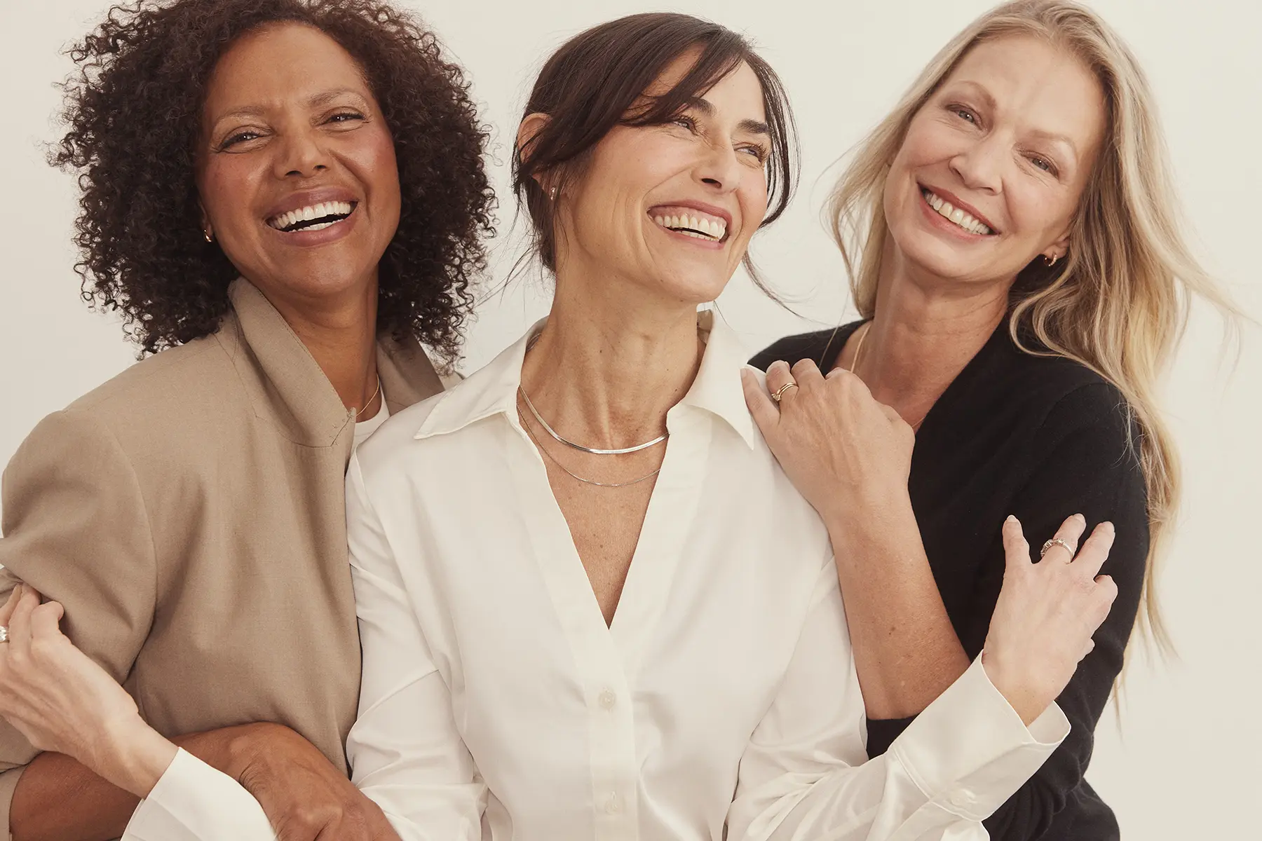 3 women in midlife holding each other and smiling