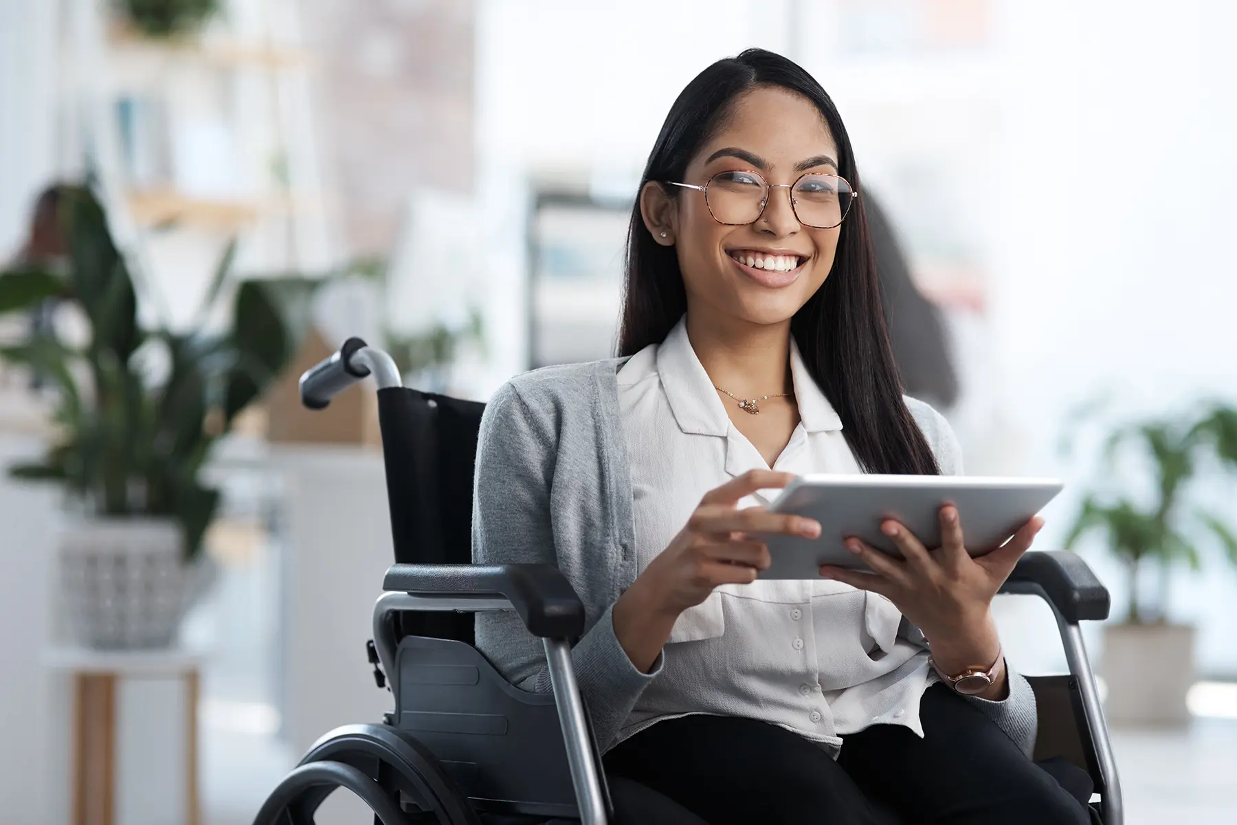 A woman sitting on a wheelchair with her tablet