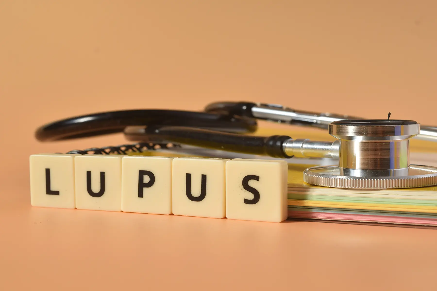 Lupus written on wooden blocks placed next to a stethoscope.