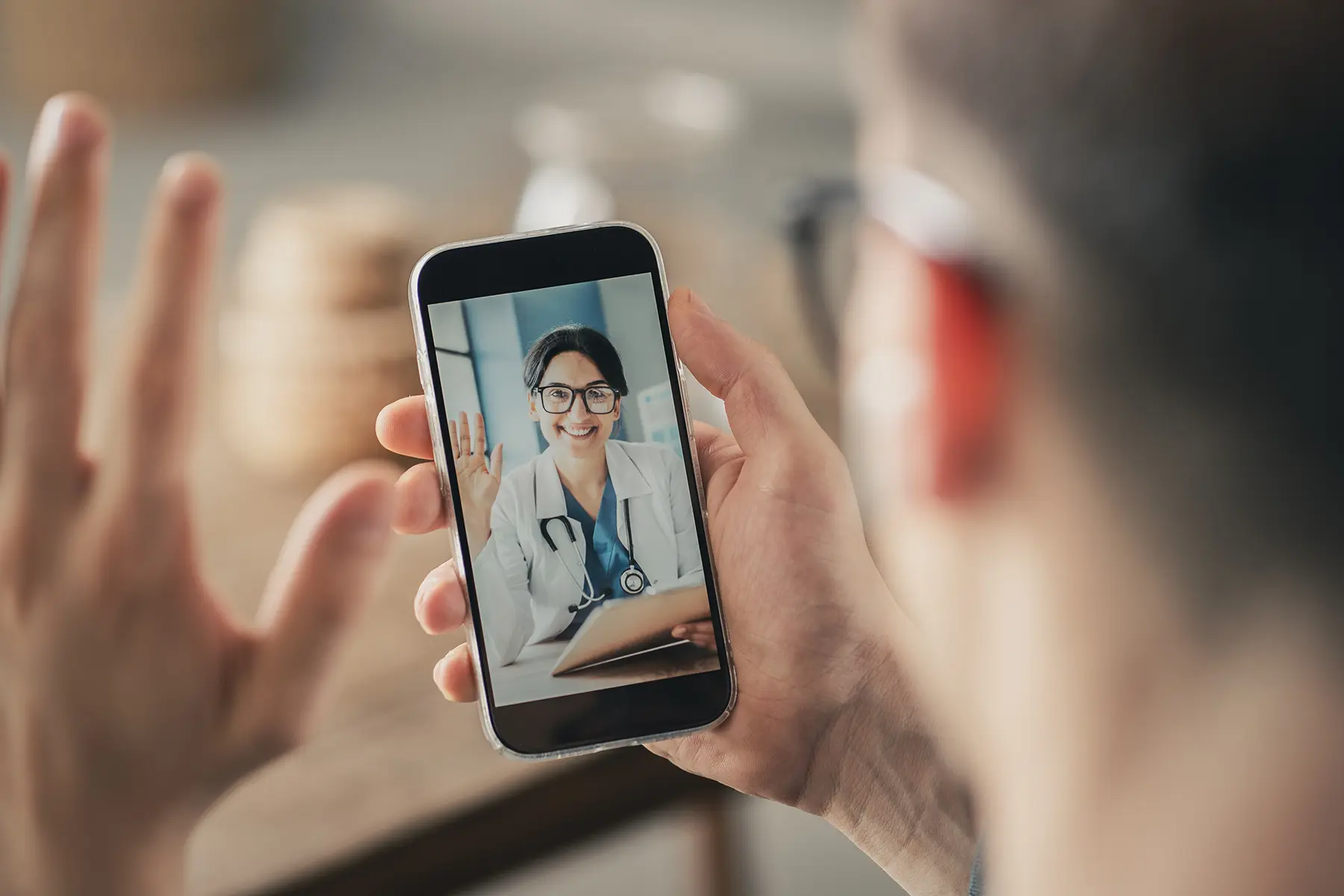 Provider and patient waving to each other via virtual telehealth call.