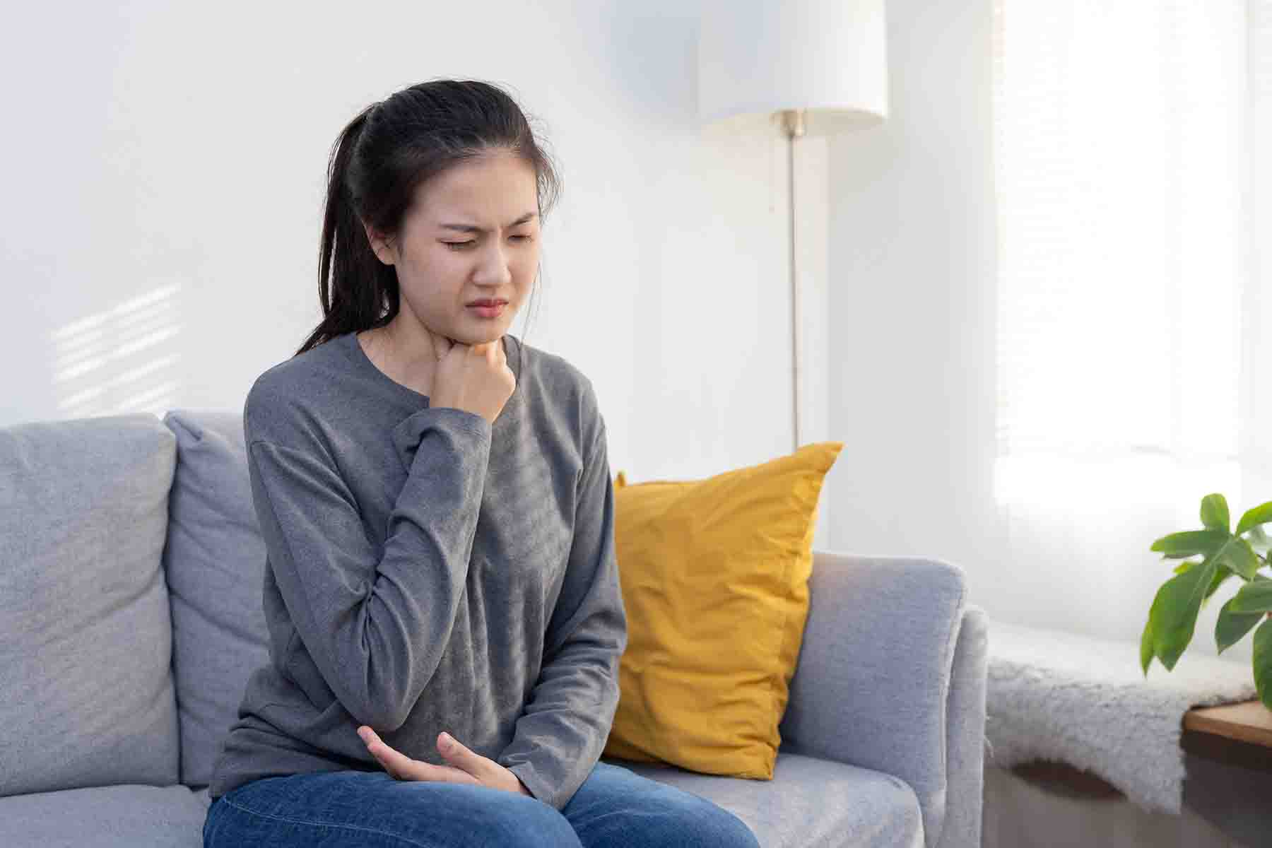 A woman touching her throat in discomfort
