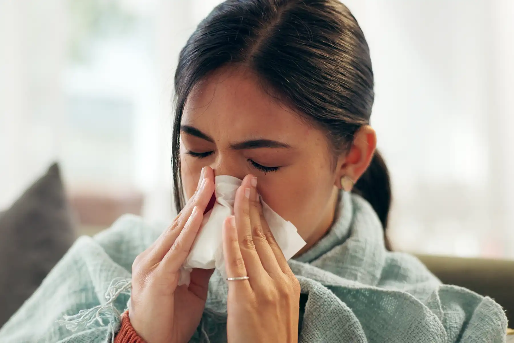 Woman sneezing into tissue