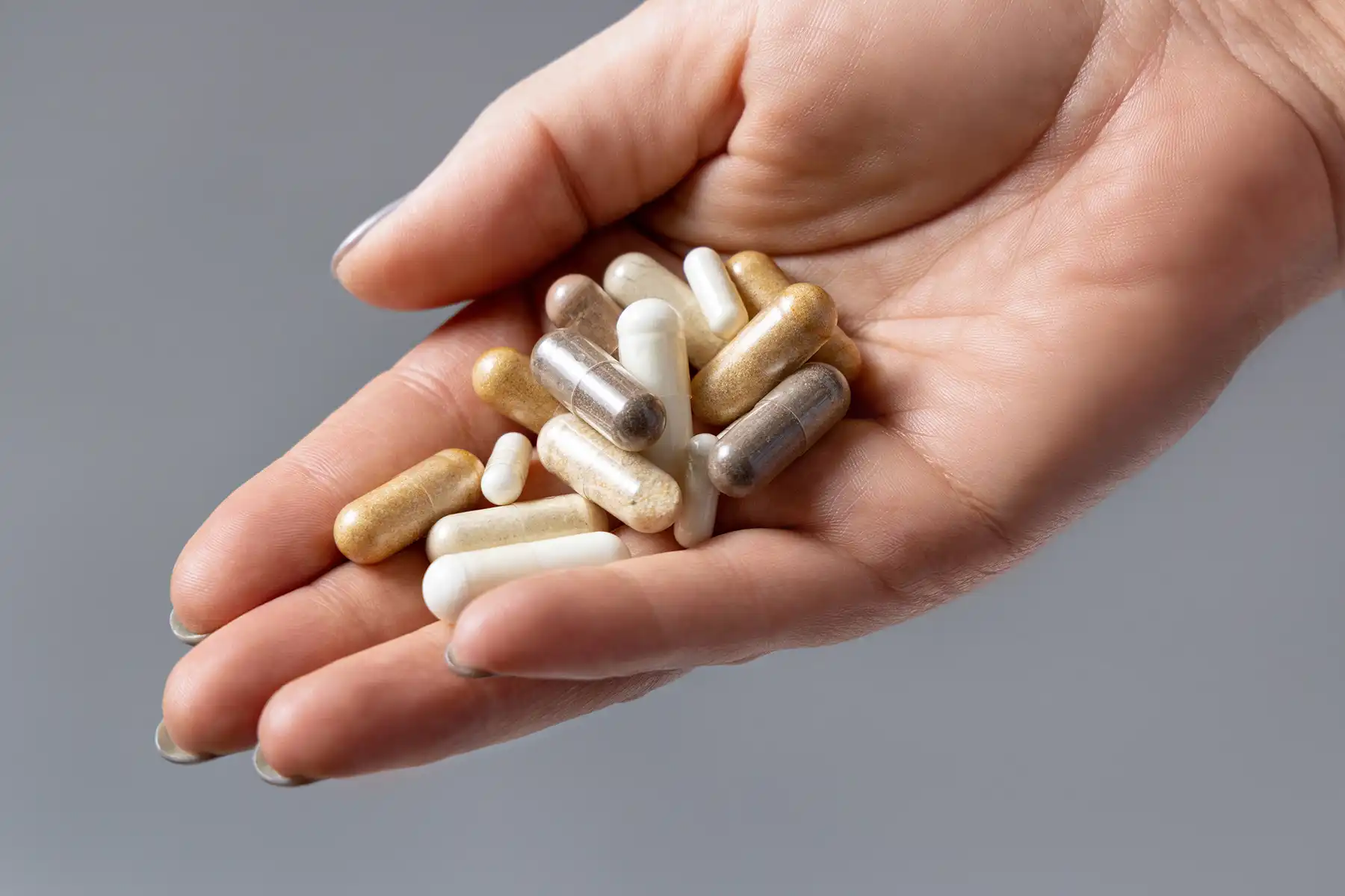 Woman's hand extended holding a variety of supplements.