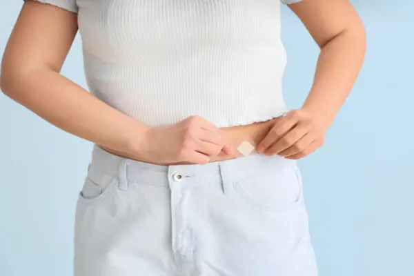 A woman putting a hormone replacement therapy (HRT) patch on her stomach