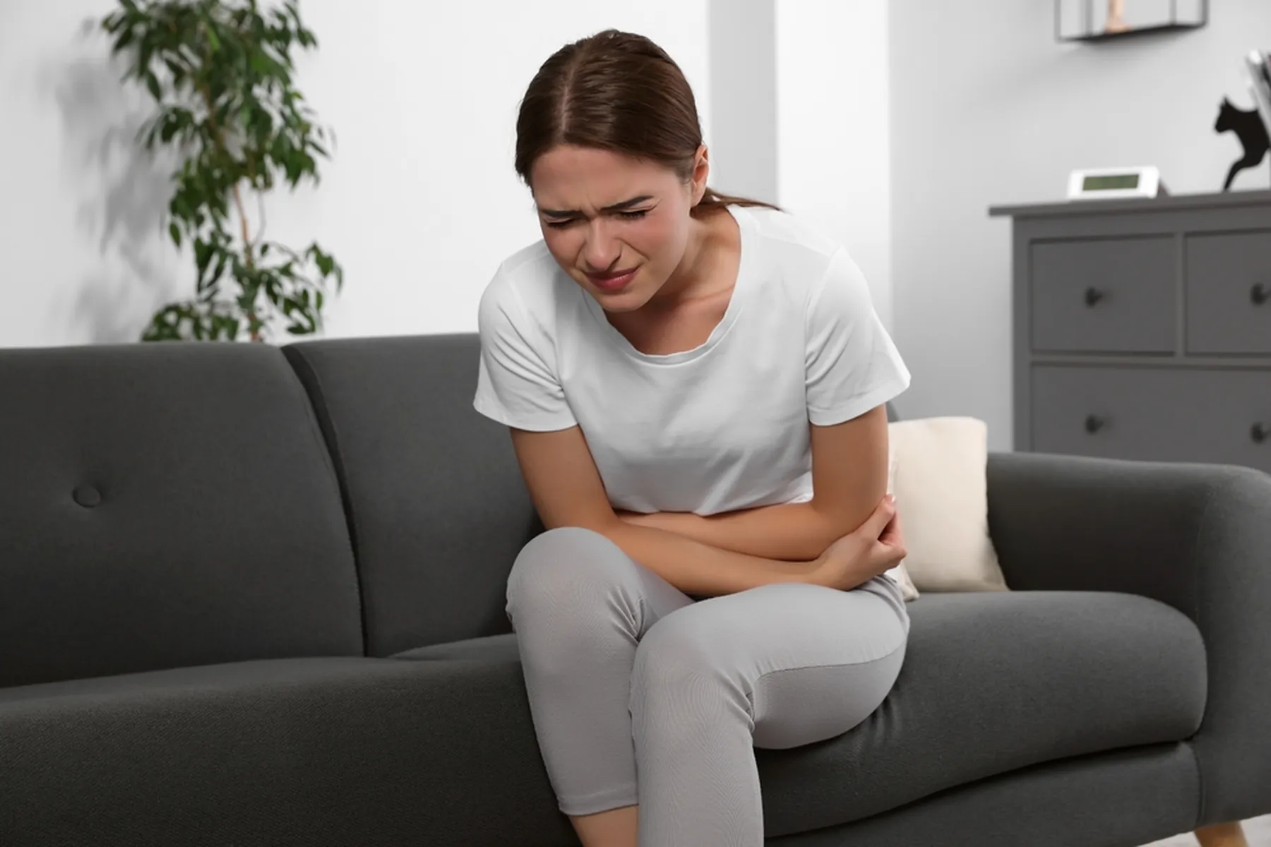 Woman clutching her lower abdomen and wincing in pain.