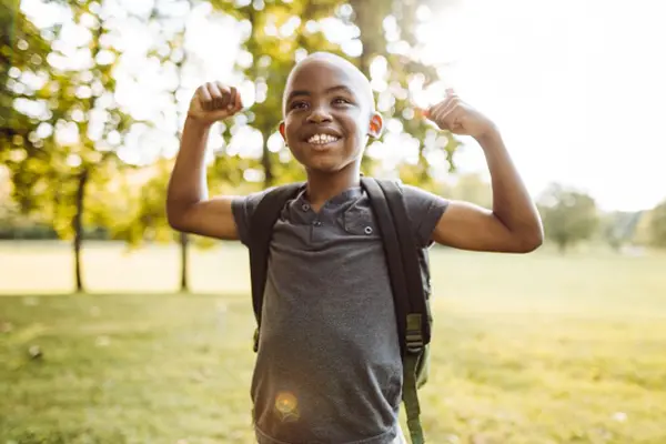 Little boy smiling and showing off his muscles.