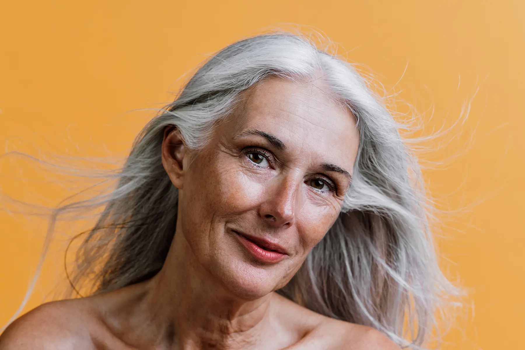 Older woman with glowing skin smiling softly.