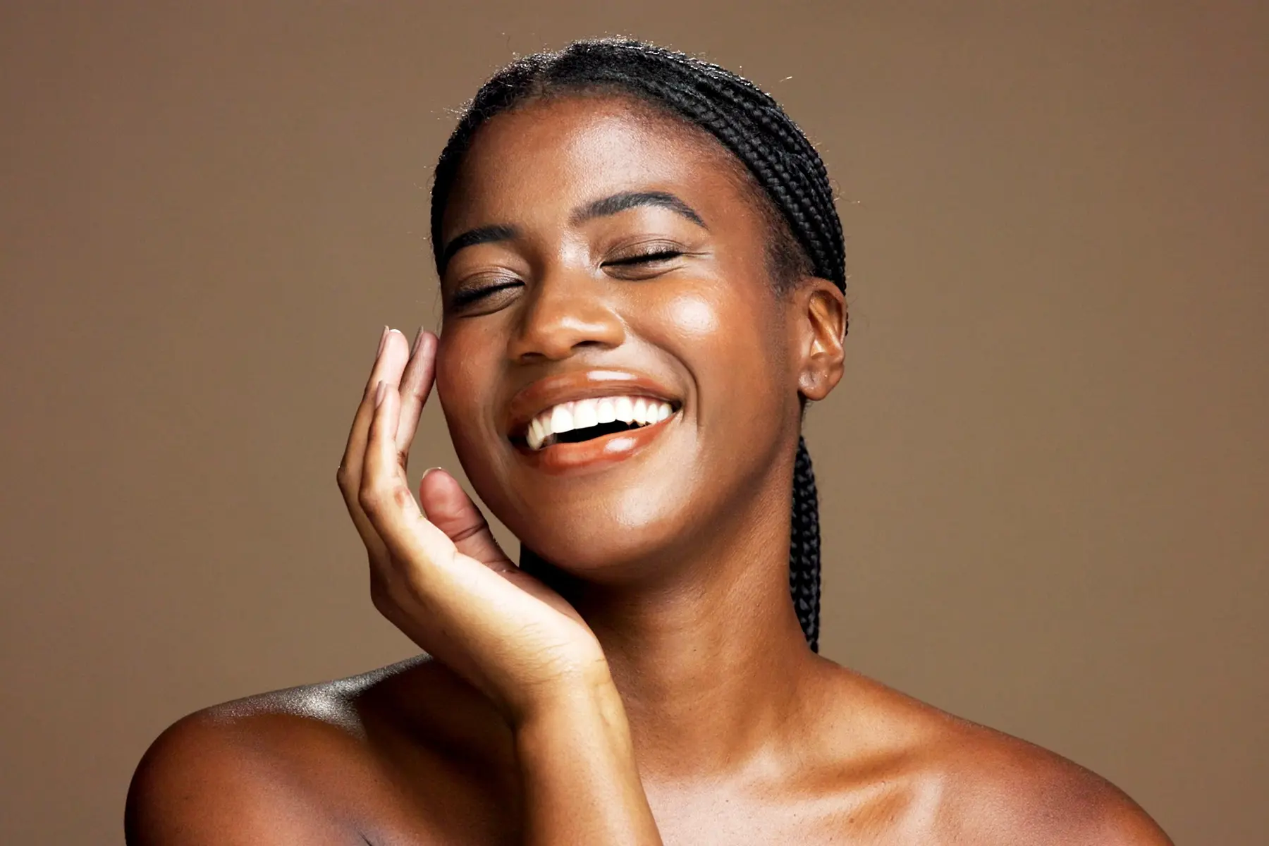 Happy woman with glowing skin touching her cheek