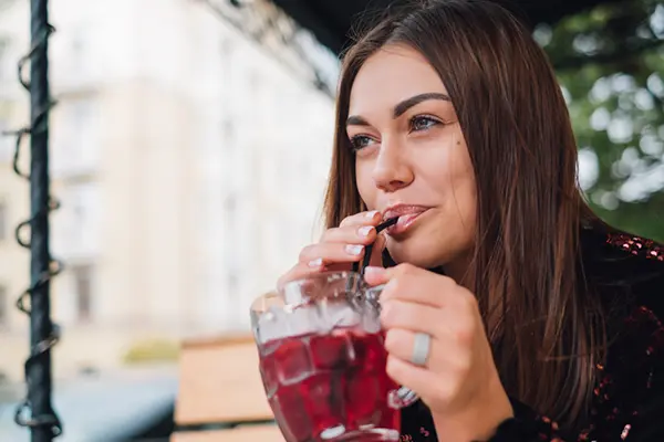 Woman sipping on cranberry juice.