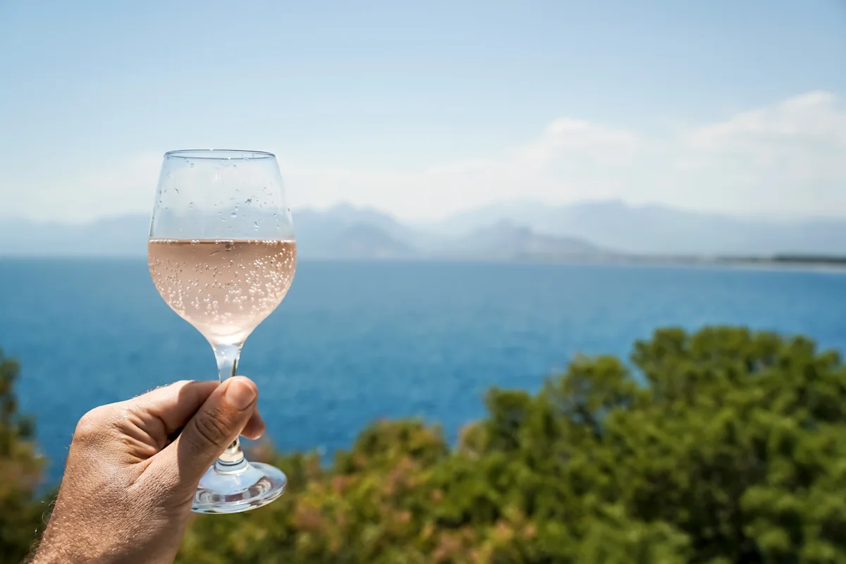 Glass of Italian rosé held up against the Mediterranean sea