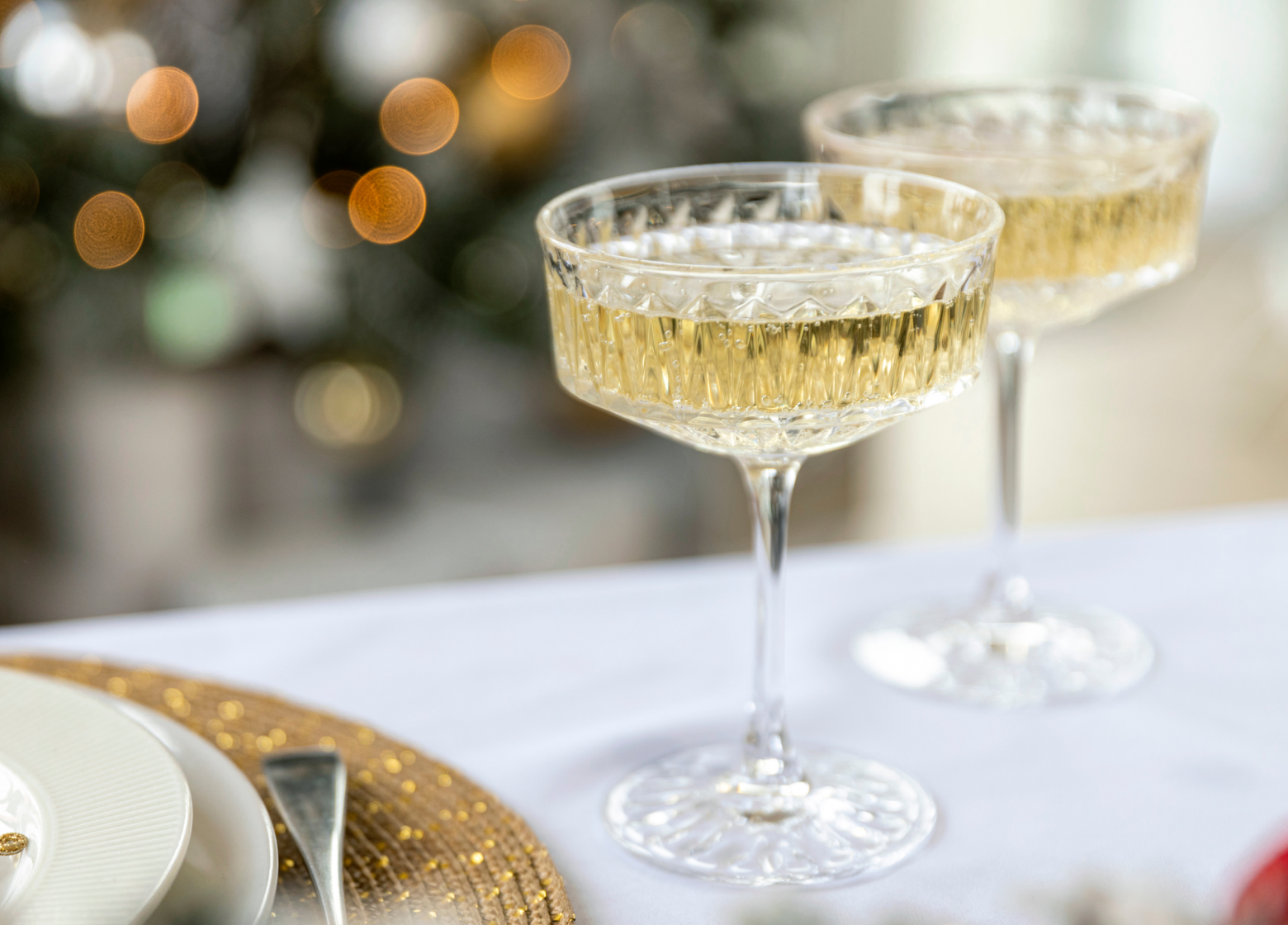 picture of champagne glasses with holiday decorations in the background