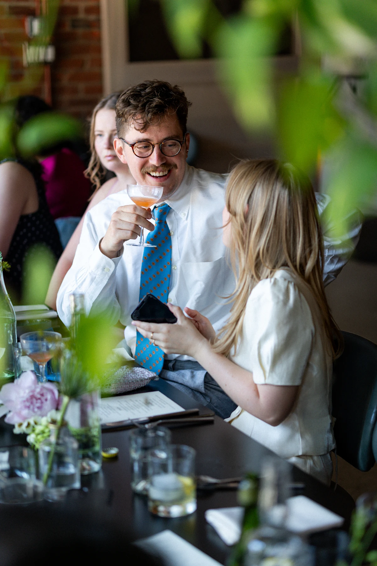 Groom smiling at bride at dinner table with a drink at Althea, Cambridge Massachusetts.