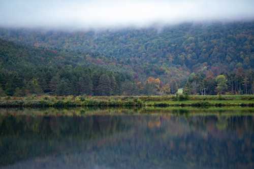 Fall foliage on a misty lake reflecting in the the water