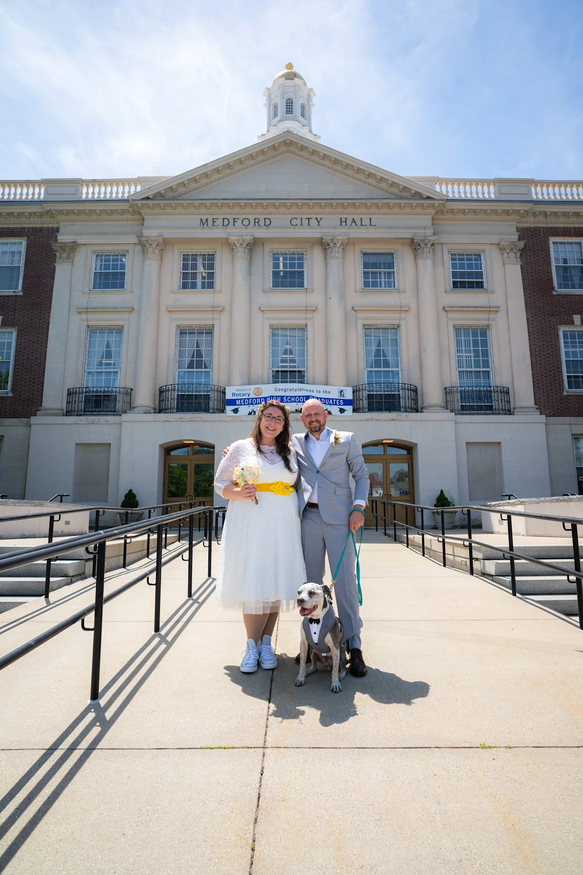 Bride and groom with dog in front of Medford, Massachusetts city hall after their elopement.