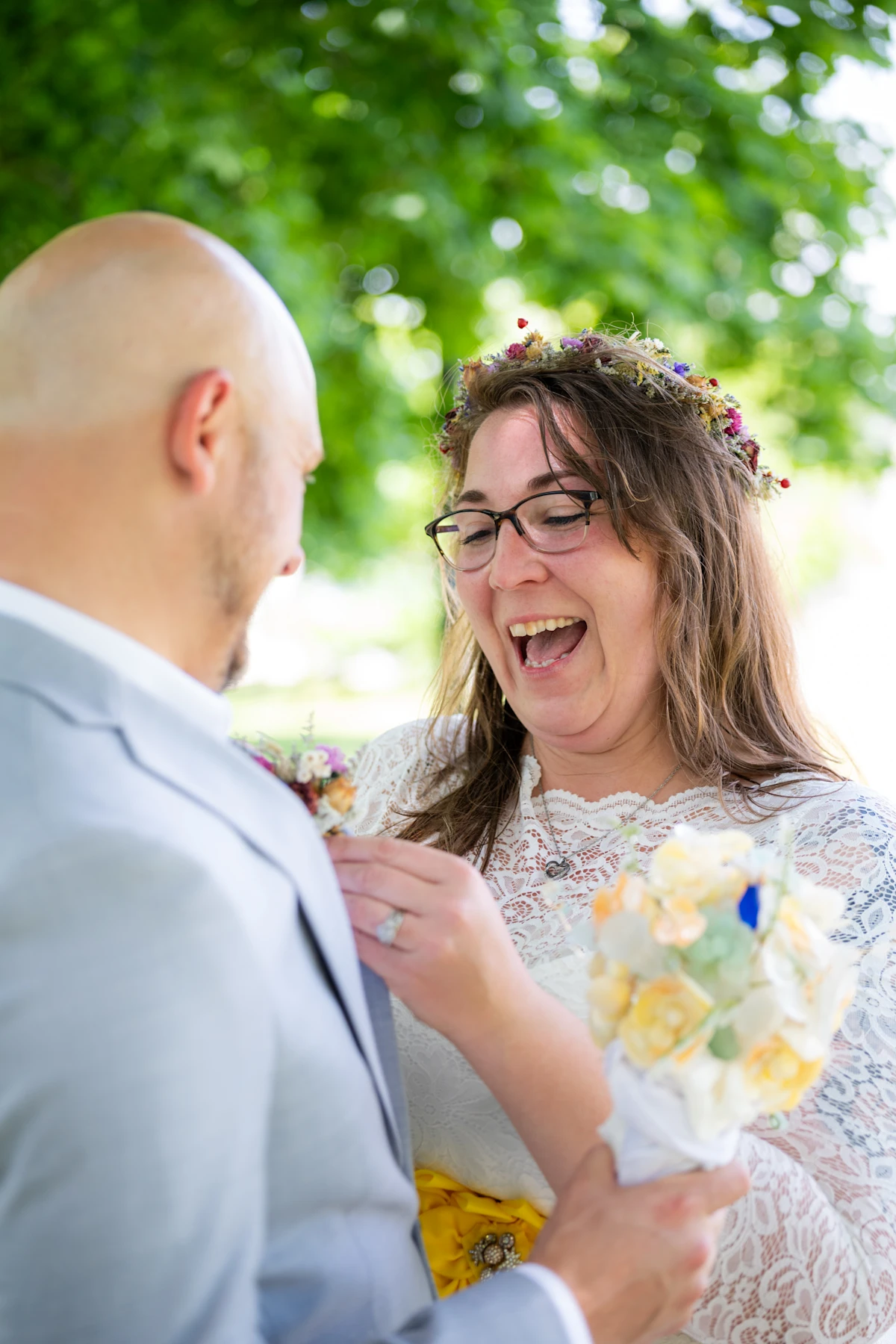 Bride laughing while she fixes the flower pin on her groom.