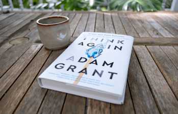 Think Again book on an outdoor table with a coffee mug