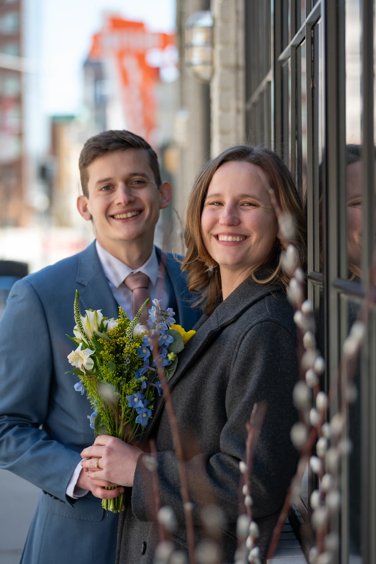 Bride and groom leaning against window with bouquet.