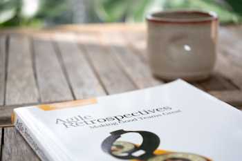 Agile Retrospectives book on an outdoor table with a coffee mug