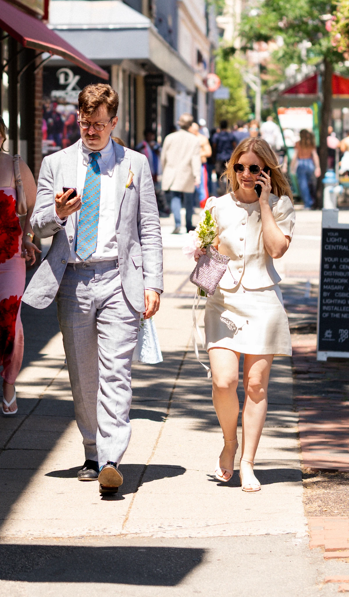 Bride and groom walking with phones in Central Square, Cambridge Massachusetts.