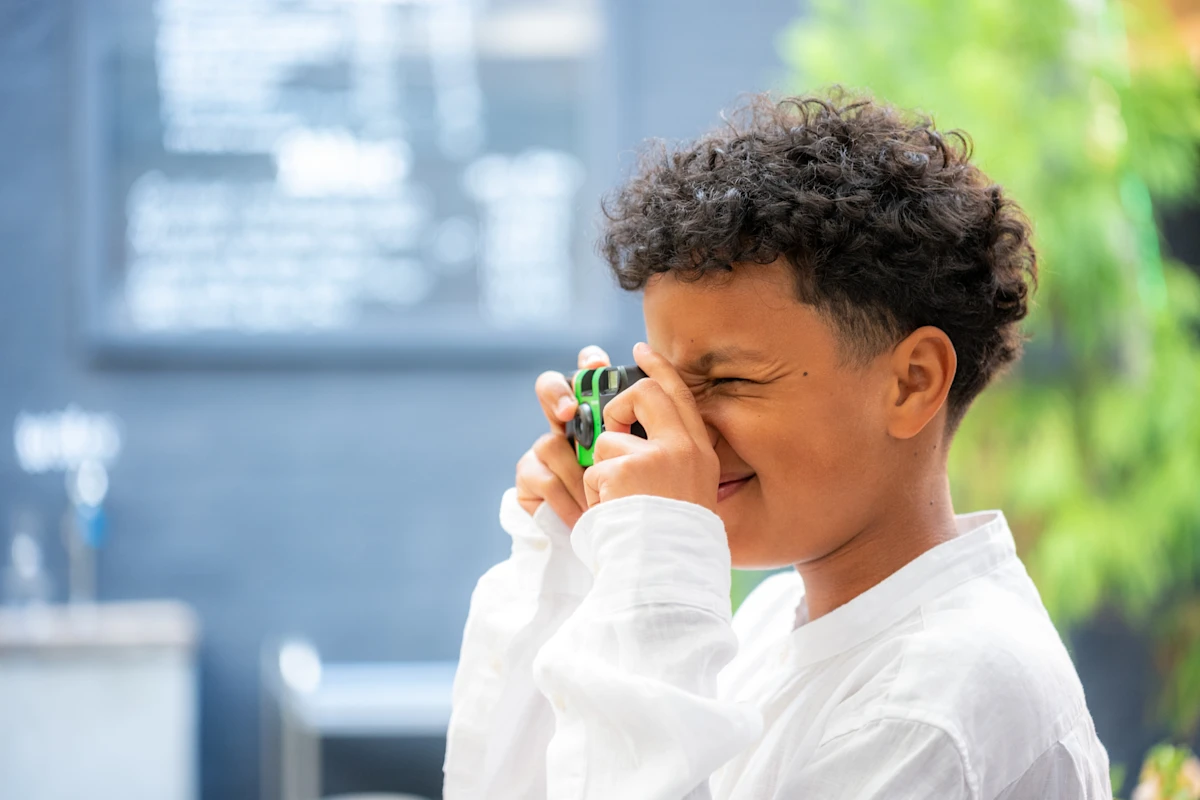 A young boy looking through the viewfinder of a disposable film camera.
