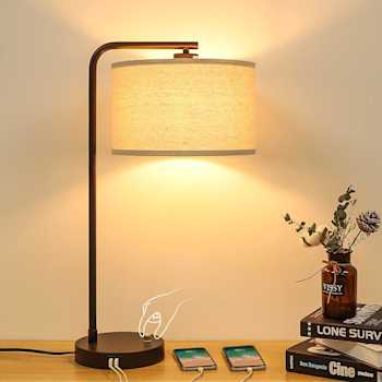 An image of a lamp emitting a warm glow, with two phones charging at its usb ports