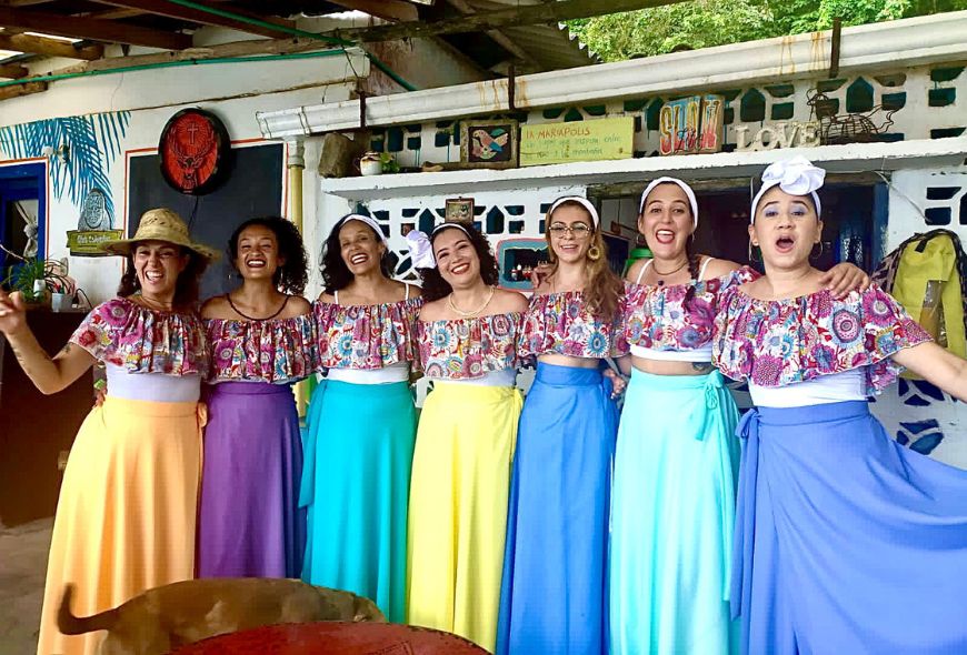 Siete mujeres sonríen a la cámara vestidas con faldas de bullerengue.
