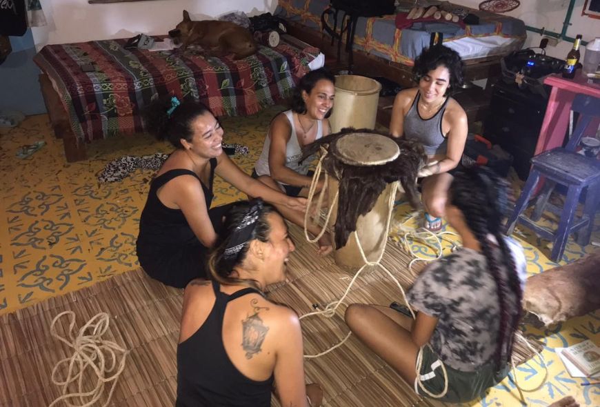 Cinco mujeres sonríen alrededor de un tambor.