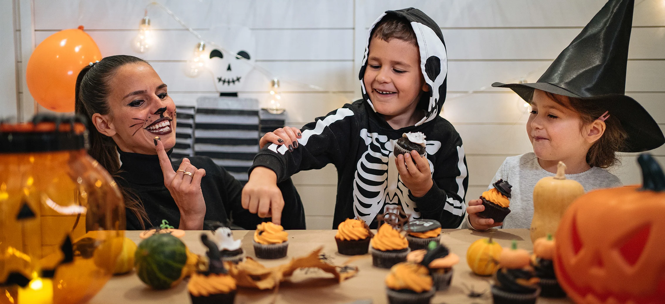 Kids dressed in Halloween costumes decorating cupcakes