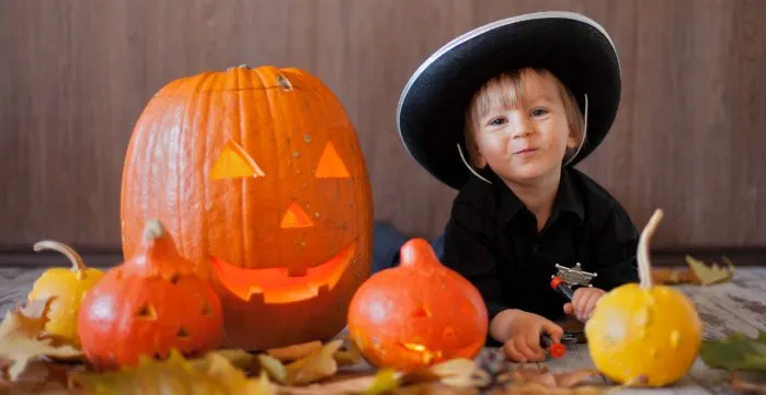 Kid sitting next to carved pumpkins