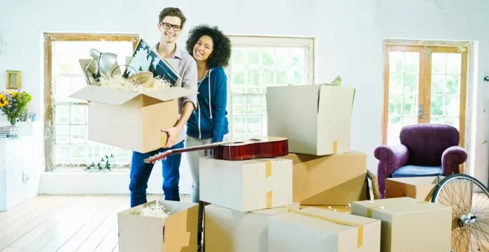 A couple standing next to boxes amid a move