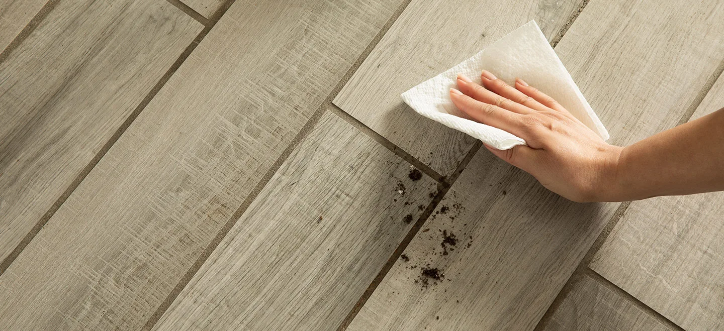 Woman's hand wiping up dirt off the floor with a Bounty paper towel