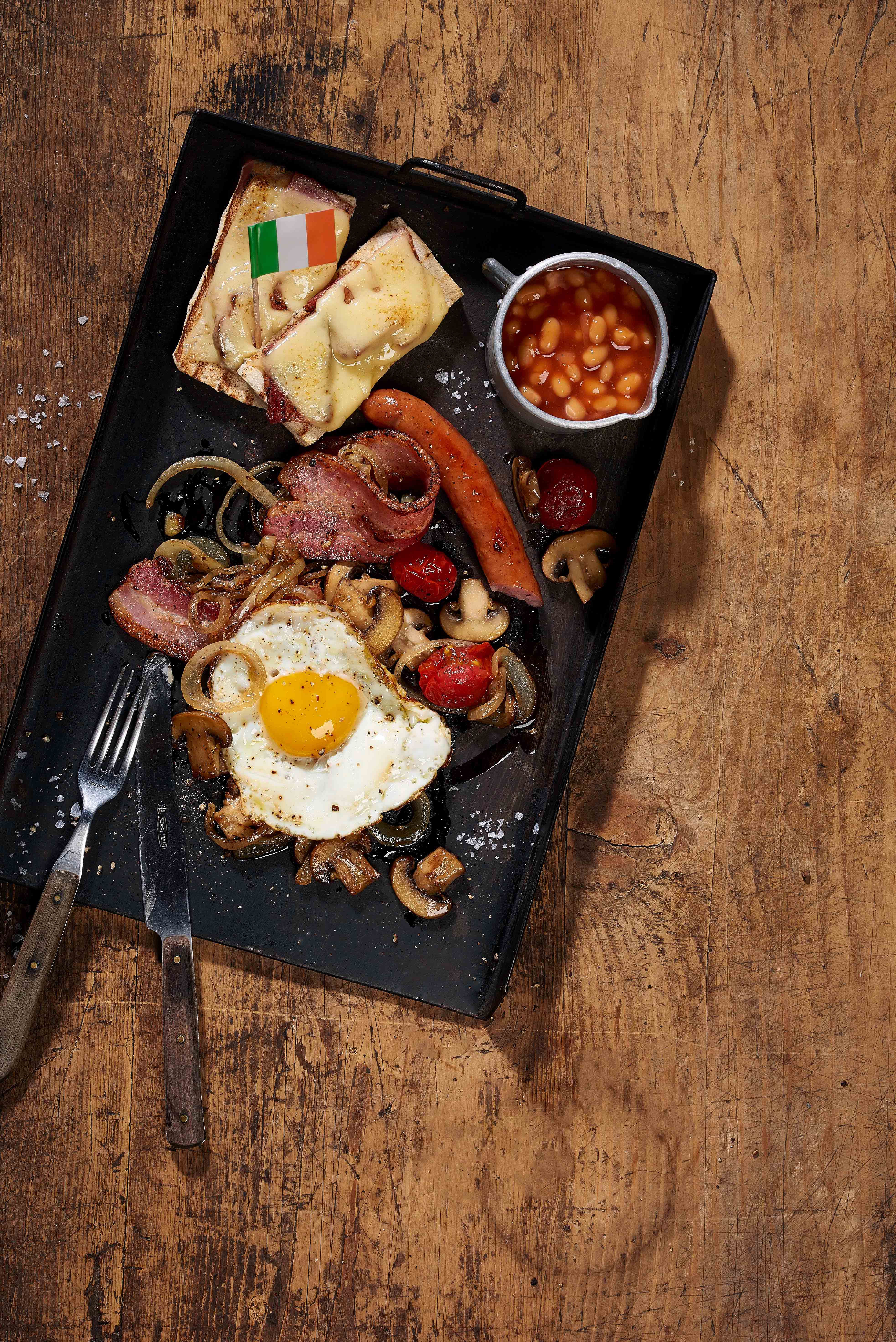 Pain grillé au fromage avec œuf au plat, saucisses, champignons et bacon