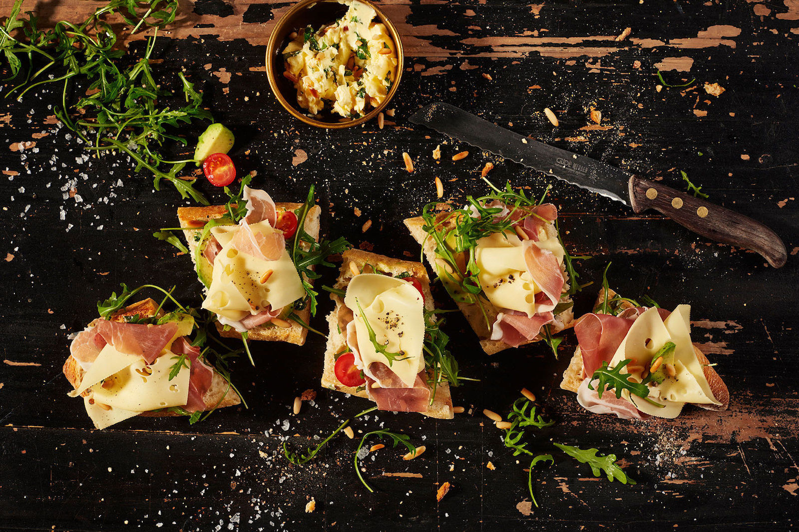 Käse-Baguette mit Basilikum-Pinienkern-Butter, Parmaschinken, Avocado, Rucola und Kirschtomaten