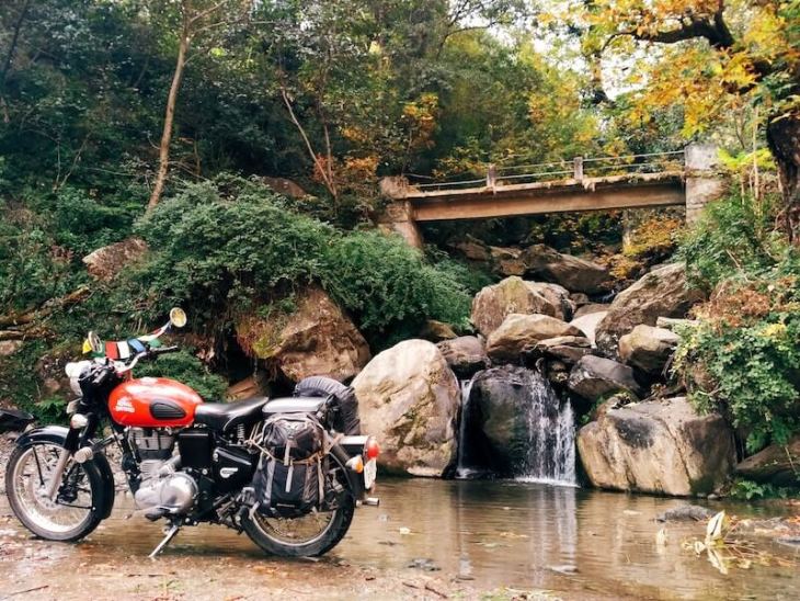 A Royal Enfield motorcycle parked in front of a waterfall