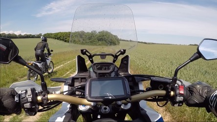 Looking out from the Africa Twins handlebars at a field and track