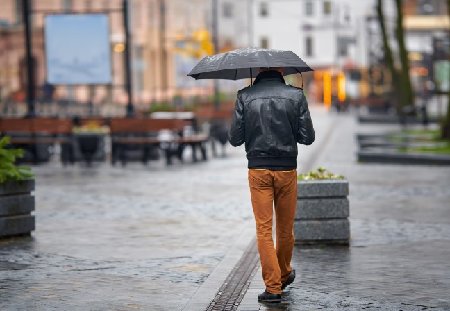 man walking in the rain with umbrella