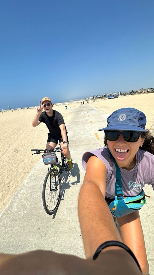 POV of person cycling on a beach following another cyclist
