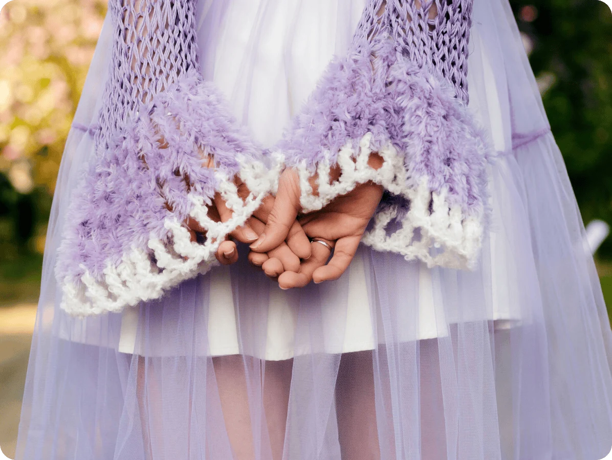 Image of a woman wearing a purple woven sweater and sheer skirt