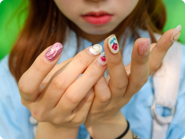 A closeup of a woman's hands with nail art featuring a red flower and a gold heart.