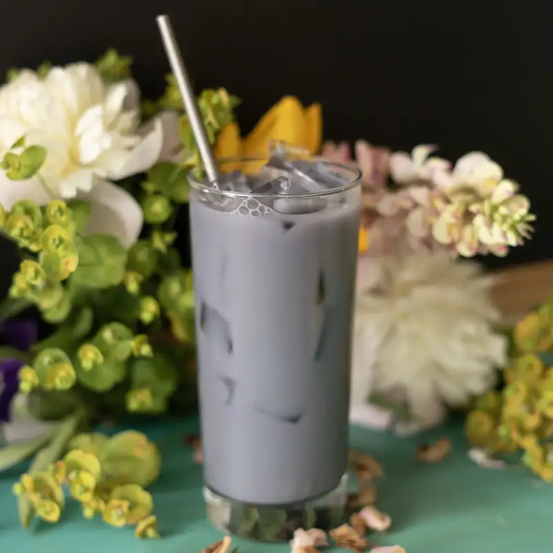 purple lavender pearl latte in a glass in front of flowers
