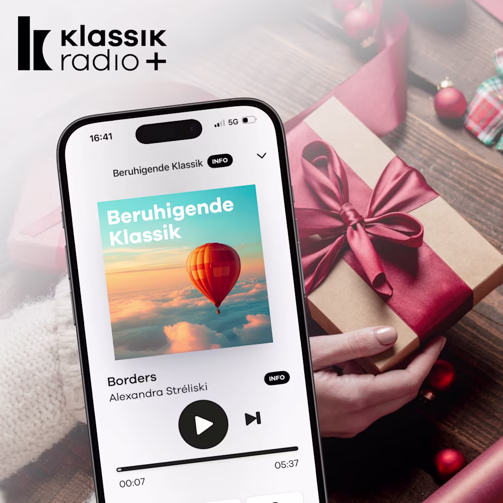 Schön eingepacktes Geschenk mit Schleife und daneben der Klassik Radio Plus Sender "Beruhigende Klassik"