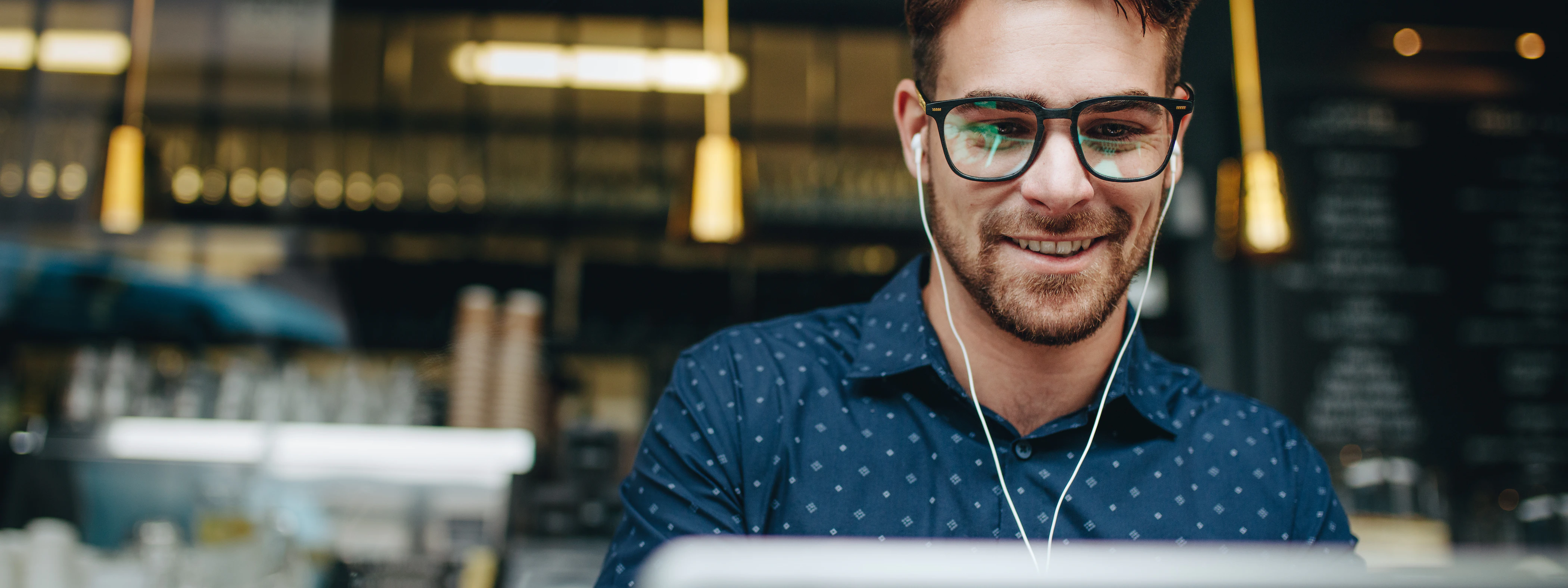 Mann mit Kopfhörern vor dem Laptop