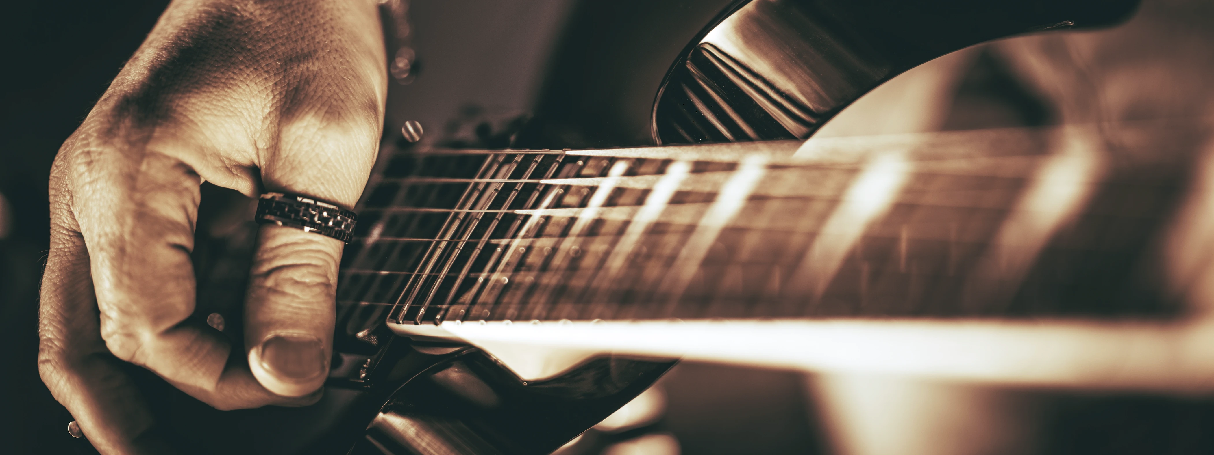 Hand zupft die Saiten einer Rock Gitarre