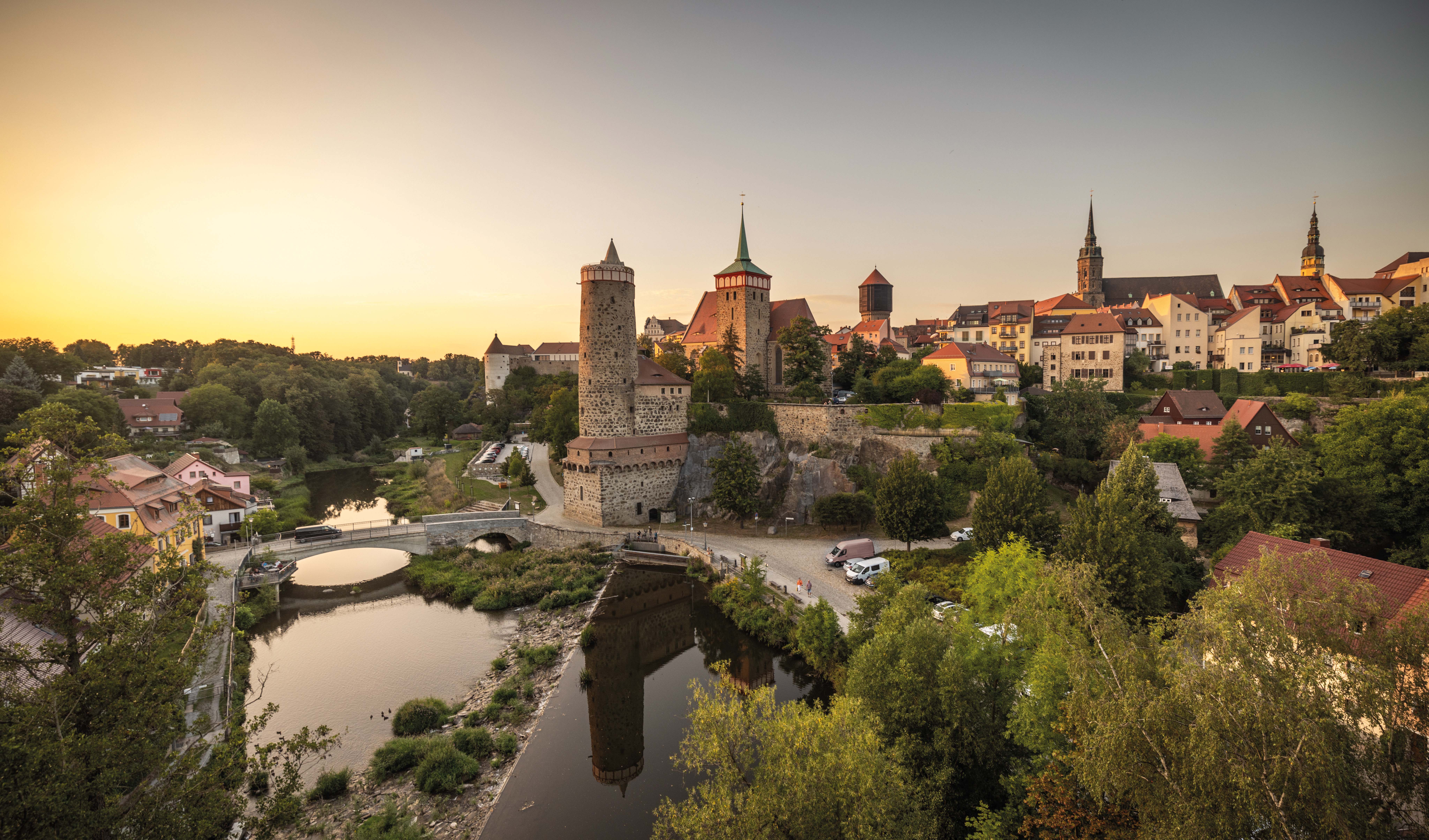 Mittelalterliche Stadt Bautzen mit Türmen und Stadtmauer am Fluss bei Sonnenuntergang